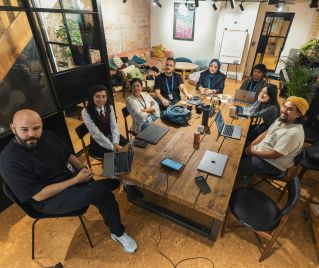 A group of diverse professionals collaborating in a modern office setting with laptops and technology.