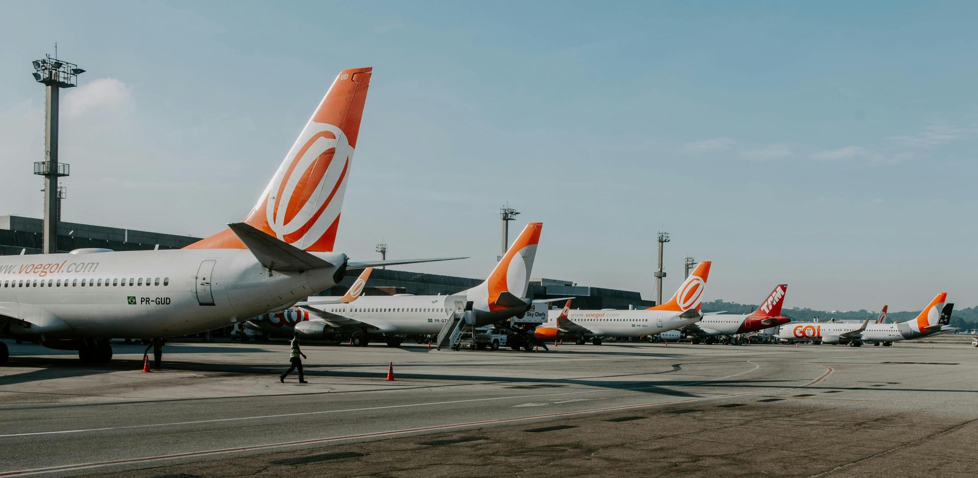 Multiple airplanes on tarmac at a busy airport during daytime, showcasing aviation and travel.